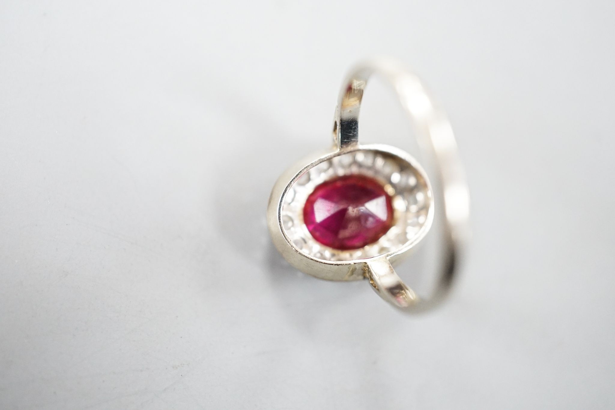 A white metal, synthetic ruby and diamond set oval cluster ring, size N, gross weight 3.4 rams.
